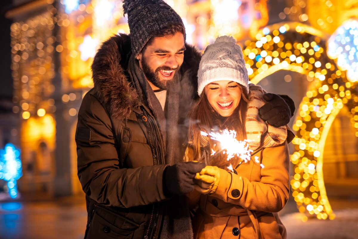 Couple holding sparkler while celebrating New Year outdoors