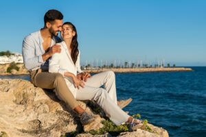 Hispanic couple in love on rocks at seaside